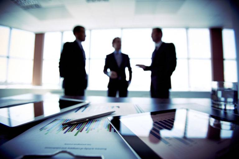 Close up documents with businessmen blurred background