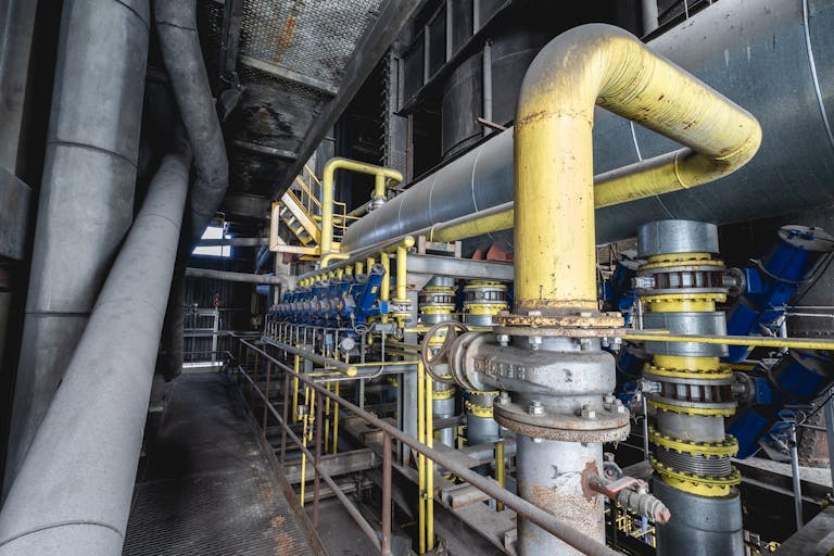 Industries 7 Close-up of an intricate industrial pipeline system featuring yellow valves and steel structures inside a factory.